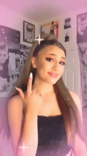 Ariana Grande Is Wearing A Black Tank Top And Making A Peace Sign . GIF
