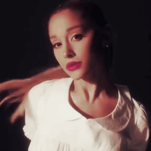 Ariana Grande Is Wearing A White Shirt And Red Lipstick And Looking At The Camera . GIF