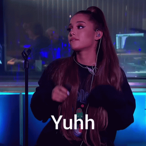 Ariana Grande Singing Into A Microphone With The Word Yuhh Written Below Her GIF