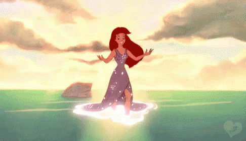 Ariel From The Little Mermaid Is Standing In The Ocean . GIF