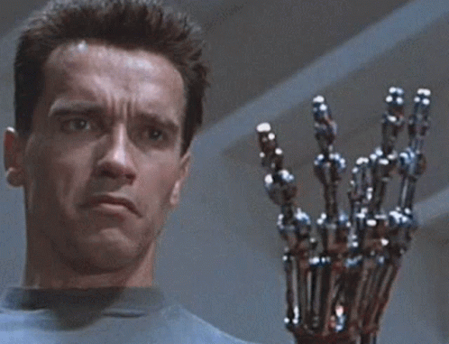 Arnold Schwarzenegger Is Holding A Robotic Arm In Front Of His Face GIF