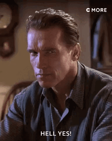 Arnold Schwarzenegger Is Sitting At A Table With A Clock In The Background . GIF