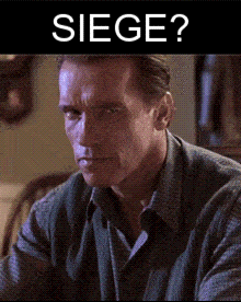 Arnold Schwarzenegger Is Sitting In Front Of A Sign That Reads Siege GIF