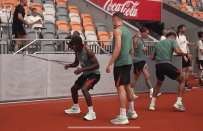 Athletes Doing Exercises in Front of Coca-Cola Sign