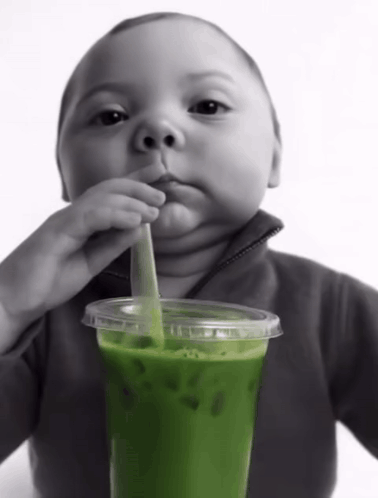 Baby Drinking Green Drink With Straw