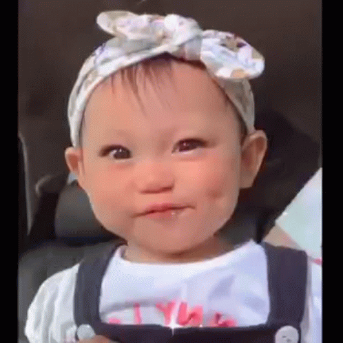 Baby Girl in Headband and Overalls Making Face