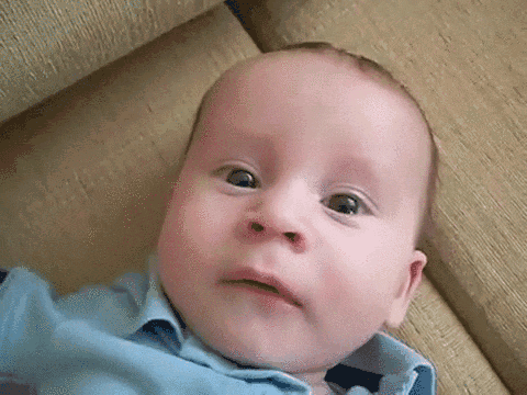 Baby in Blue Shirt on Couch Making Funny Face