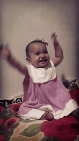 Baby in Pink Dress Sitting on Bed