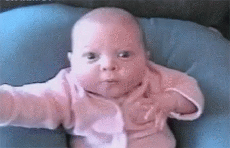 Baby In Pink Shirt Sitting On Blue Pillow GIF