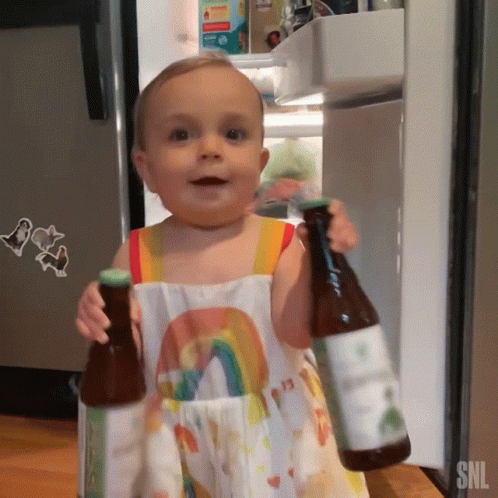 Baby in Rainbow Dress Holding Two Bottles SNL