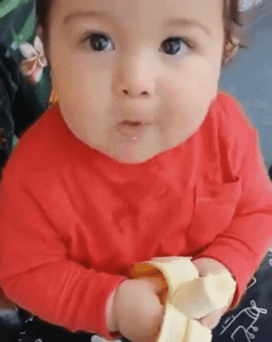 Baby In Red Shirt Eating Banana Peel GIF