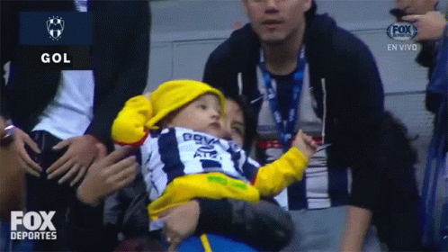 Baby in Yellow Hat Held by Man in Fox Deportes Ad