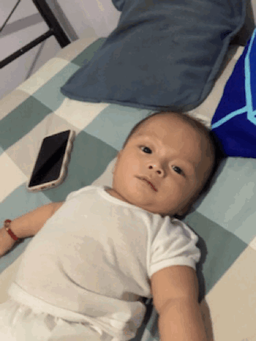Baby Lying on Bed Next to Cellphone