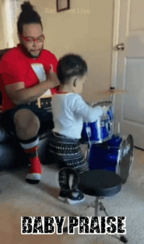 Baby Playing Drums With Man Behind
