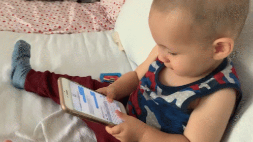 Baby Playing With Cellphone On Bed GIF