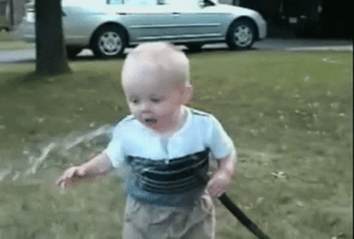 Baby Playing with Hose in Park