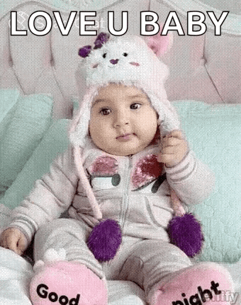 Baby Sitting In Cat Hat And Slippers On Bed GIF
