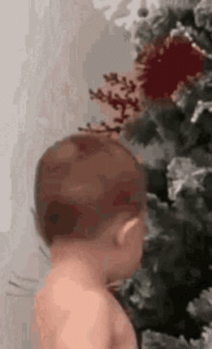 Baby Standing Next to Christmas Tree