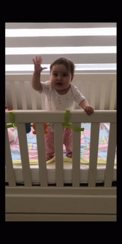 Baby Waving In White Crib GIF