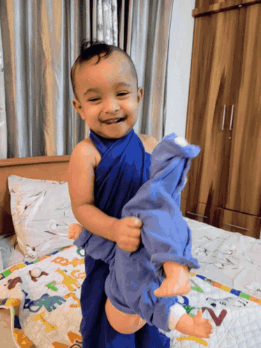 Baby Wrapped in Blue Holding Doll