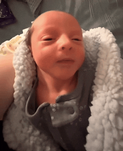 Baby Wrapped in White Blanket Looking at Camera