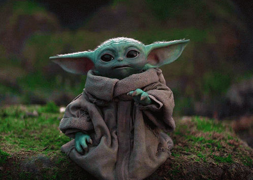 Baby Yoda Figurine Sitting On Mossy Rock GIF