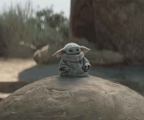 Baby Yoda Toy Sitting on Large Rock