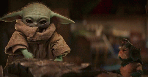 Baby Yoda Toy Sitting on Rock