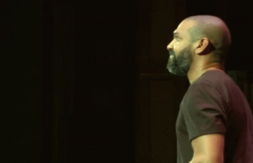 Bald Bearded Man Raising Hand in Dark