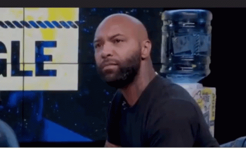 Bald Bearded Man Sitting in Front of Gle Wall