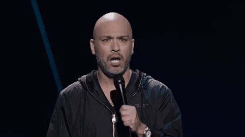 Bald Bearded Man Speaking Into Microphone With Watch