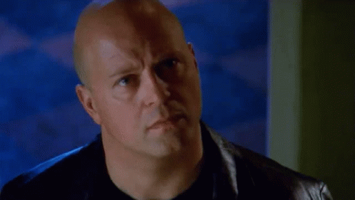 Bald Man in Black Shirt and Leather Jacket Looking at Camera