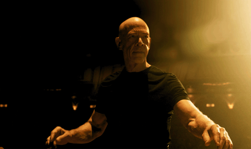 Bald Man in Black Shirt Standing in Dark Room