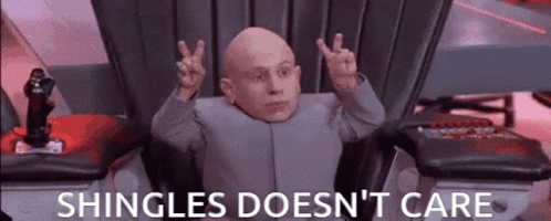 Bald Man in Chair With Hands Up Shingles Doesn't Care