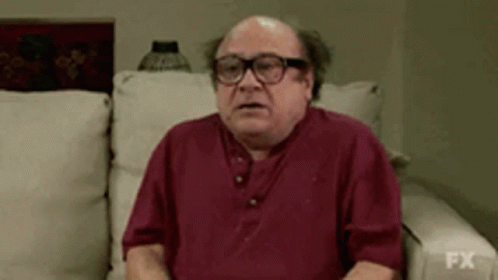 Bald Man In Glasses And Red Shirt Sitting On Couch GIF