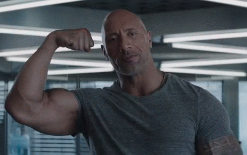 Bald Man In Gray Shirt Flexing Muscles GIF