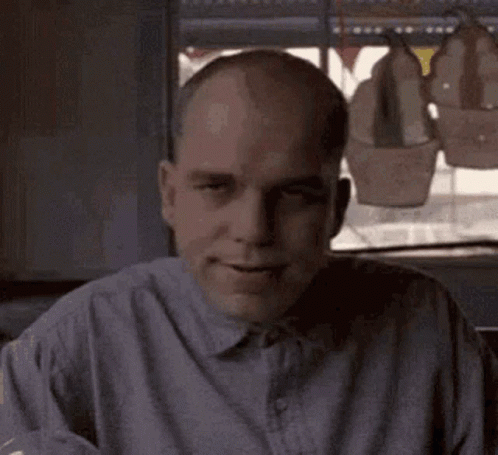 Bald Man In Gray Shirt Sitting By Window GIF