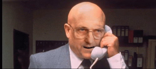 Bald Man in Suit and Glasses Talking on Phone