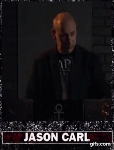 Bald Man in Suit Standing by Laptop