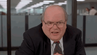 Bald Man in Suit, Tie, and Glasses at Desk