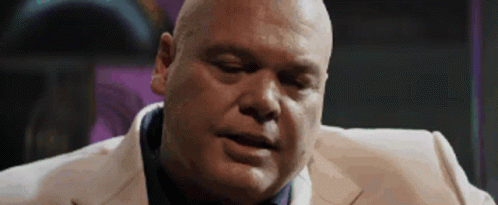 Bald Man in White Suit and Blue Tie Looking Down