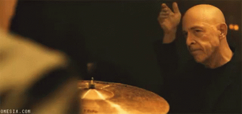 Bald Man Playing Drums in Dark Room