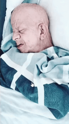 Bald Man Sleeping in Bed With Nike Blanket