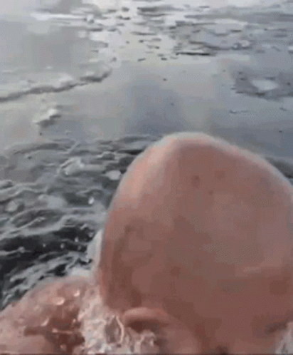 Bald Man Swimming with Ice on Head