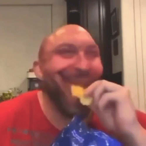 Bald Man with Beard Eating Chips and Smiling