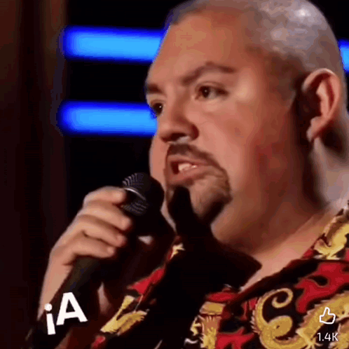 Bald Man With Beard Singing Into Microphone in Colorful Shirt