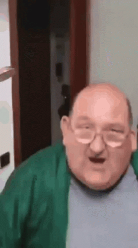 Bald Man With Glasses and Green Sweater Making Funny Face