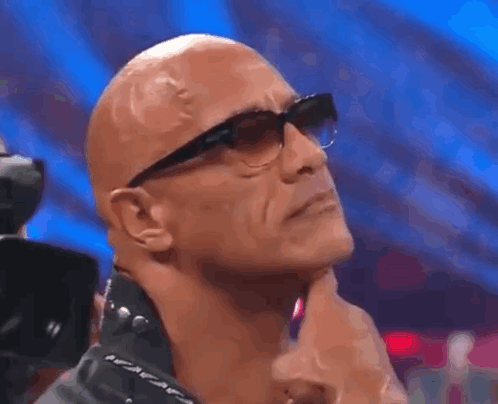 Bald Man With Glasses And Leather Jacket Hand On Chin GIF
