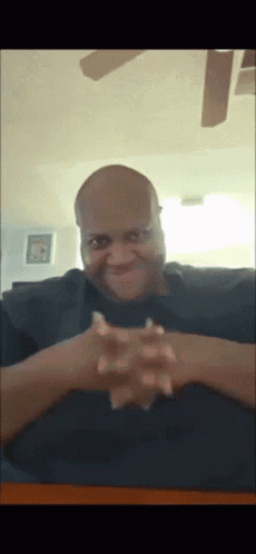 Bald Man with Hands Folded at Table
