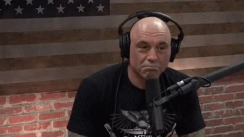 Bald Tattooed Man Covering Head at Microphone